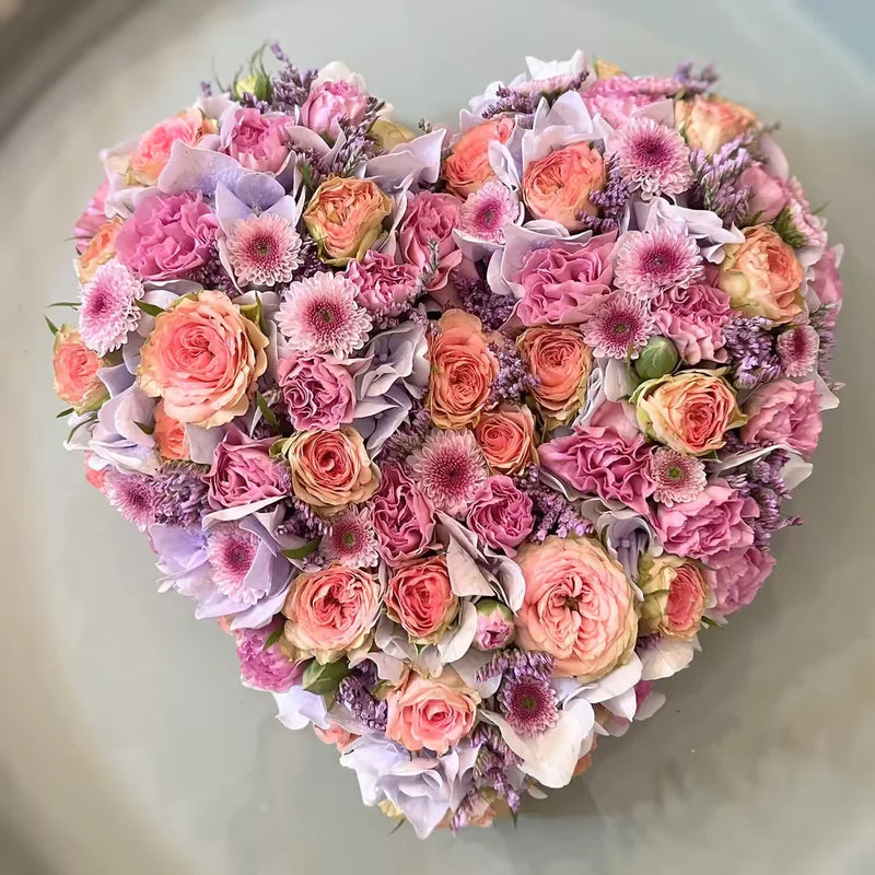 Handgearbeitetes Blumengesteck in Herzform – liebevoll komponiert für besondere Anlässe